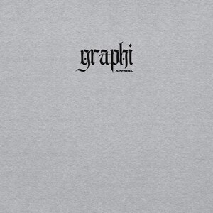 May include: A pale grey t-shirt featuring the word "graphi" in a gothic font, with the word "apparel" beneath it. The text is black. The shirt has a plain, solid colour.