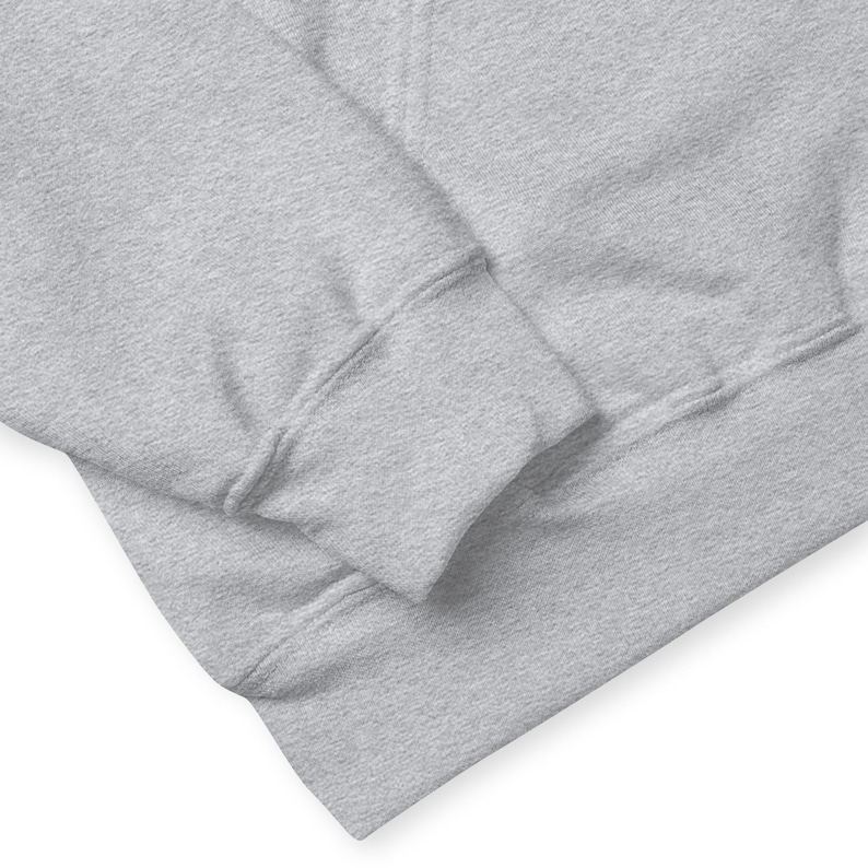 May include: Close-up of a light grey hoodie. The image focuses on the sleeve and the lower portion of the hoodie, showcasing the ribbed cuff and the soft, textured fabric. The hoodie appears to be made of a comfortable material.