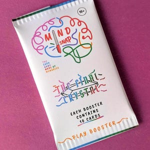 May include: A white card game booster pack with the text "MIND SNAP" and "THE FINAL CRYSTAL" in colorful lettering. The pack also includes the text "EACH BOOSTER CONTAINS 10 CARDS" and "PLAY BOOSTER". The background is a solid magenta color.