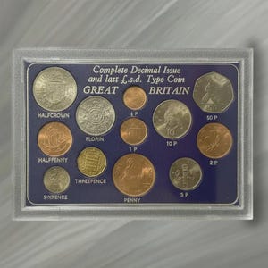May include: A collection of British coins, including a Halfcrown, Florin, and Penny, displayed in a clear plastic case. The coins are in various sizes and colors, with text that reads "Complete Decimal Issue" and "Great Britain."