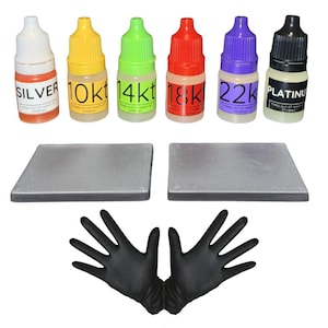 May include: A jewelry testing kit with six small bottles labeled "Silver", "10k", "14k", "18k", "22k", and "Platinum". Two gray testing stones and a pair of black gloves are also included. The bottles have different colored caps.