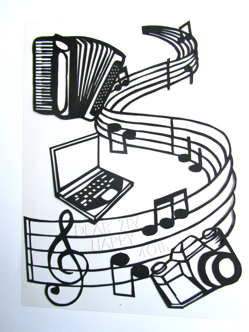 May include: Black and white paper cut-out art featuring a musical staff with treble clef, musical notes, an accordion, a laptop, and a camera. The text "Dear Ziv Happy 40th" is written on the staff.