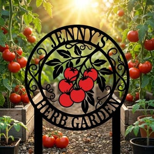 May include: Black metal garden stake with the text "Jenny's Herb Garden" in a circular design, featuring red tomatoes and green leaves. The stake is in a garden with tomato plants and ripe red tomatoes.