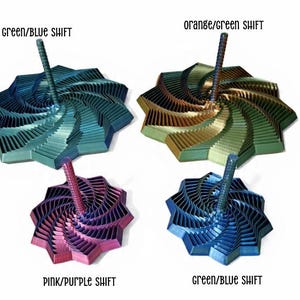 May include: Four colorful, geometric tops with a spiral design. The tops are in shades of green, blue, orange, pink, and purple. Each top has a central rod. The text "green/blue shift", "orange/green shift", and "pink/purple shift" is visible.