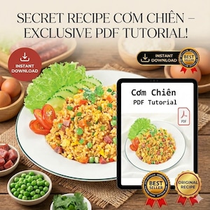May include: A plate of fried rice with vegetables and meat, served with fresh lettuce and tomatoes. The image also features a digital tablet displaying a PDF tutorial for the recipe, with the text "Cơm Chiên PDF Tutorial".