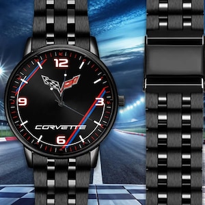 Könnte beinhalten: Schwarze Armbanduhr mit passendem Armband. Das Zifferblatt zeigt das Corvette-Logo, rote und blaue Akzente und weiße Ziffern. Das Armband hat ein sich wiederholendes rechteckiges Muster.