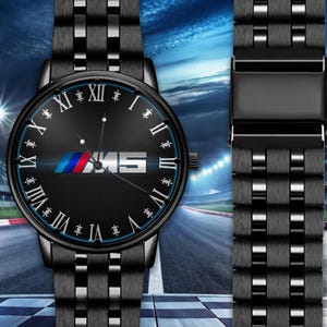 May include: Black wristwatch with a black band and a black watch face. The watch face features the BMW logo in blue, red, and white, along with the letters "M5" in white. The watch has Roman numeral hour markers.