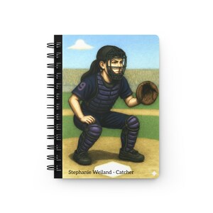 May include: Spiral-bound notebook featuring an illustration of a baseball catcher in a crouched position. The catcher wears a black helmet, chest protector, and leg guards, with the number 9 on the uniform. The text "Stephanie Weiland - Catcher" is printed at the bottom.