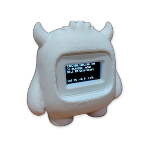 Könnte beinhalten: Ein weißes, 3D-gedrucktes Radio in Monsterform mit einem digitalen Bildschirm, der den Text 192.168.188.190 -84, >> PLAYING #FAV, 94.1 FM Gold Coast sowie vol 7% rb 0 117k anzeigt. Das Gerät hat zwei Hörner und einen abgerundeten, texturierten Körper.