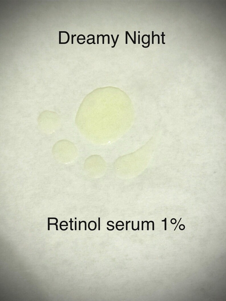 May include: A close-up of a light-colored liquid serum with the text "Dreamy Night" and "Retinol serum 1%" in black. The serum is in several small droplets on a white surface.