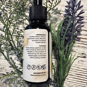 May include: A black glass bottle with a dropper, surrounded by lavender and greenery. The label lists ingredients: Distilled Water, Retinol, Hyaluronic Acid, Glycerin, and Leucidal Complete Preservatives. The label also includes a caution and the distributor's name.
