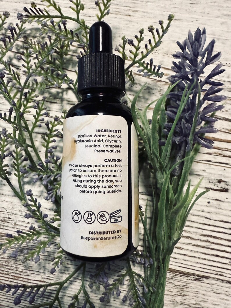 May include: A black glass bottle with a dropper, surrounded by lavender and greenery. The label lists ingredients: Distilled Water, Retinol, Hyaluronic Acid, Glycerin, and Leucidal Complete Preservatives. The label also includes a caution and the distributor's name.