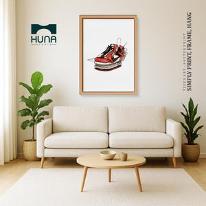 Puede incluir: Una impresión artística enmarcada con una ilustración de zapatilla deportiva roja y negra. La obra de arte es un dibujo lineal, con los detalles del zapato delineados sobre un fondo blanco. El marco es de color marrón claro. El texto a la derecha dice: SIMPLY PRINT, FRAME, HANG.