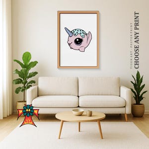 Può includere: Una stampa artistica incorniciata con un narvalo dei cartoni animati con un corpo rosa, un corno blu e un motivo a pois blu e bianchi sulla testa. La stampa è esposta su una parete bianca sopra un divano beige. Il testo "CHOOSE ANY PRINT" è visibile.