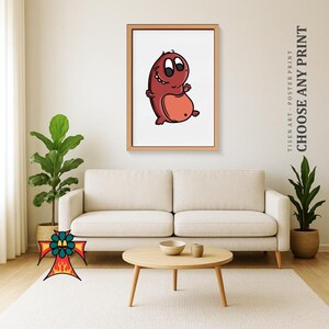 May include: A framed print featuring a cartoon monster with a red body and a lighter red belly. The monster has large eyes and a friendly expression. The frame is a light brown color. The text "CHOOSE ANY PRINT" is visible on the right side of the image.