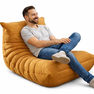 May include: Mustard-colored, modern-style lounge chair with a low profile and a textured, ribbed design. The chair is made of a soft, plush material and is designed for comfort and relaxation. The chair is perfect for a living room or den.