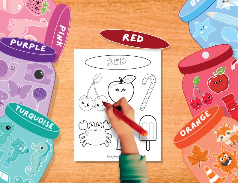 Puede incluir: Una mano infantil colorea una p&aacute;gina con un rotulador rojo. La p&aacute;gina presenta dibujos lineales de una cereza, una manzana y un bast&oacute;n de caramelo, con la palabra "RED" en la parte superior. Frascos coloridos con etiquetas de colores rodean la p&aacute;gina.