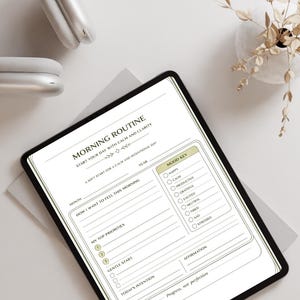 May include: A digital tablet displaying a "Morning Routine" planner with sections for mood, priorities, and intentions. The text includes "Start your day with calm and clarity." A pair of white headphones and a vase with dried flowers are also visible.