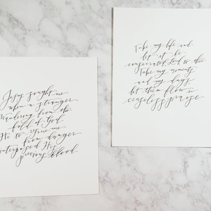 May include: Two black and white calligraphy prints with inspirational quotes. The first print reads "Jesus sought me when a stranger wandering from the fold of God He to rescue me to from danger interposing His precious blood." The second print reads "Take my life and let it be consecrated, Lord, to thee. Take my moments and my days, let them flow in ceaseless praise."