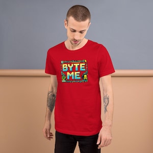 May include: A red t-shirt featuring the text "BYTE ME" in a pixelated design with blue, yellow, and green accents. The graphic includes computer-themed elements like a skull and crossbones, a monitor, and a keyboard.