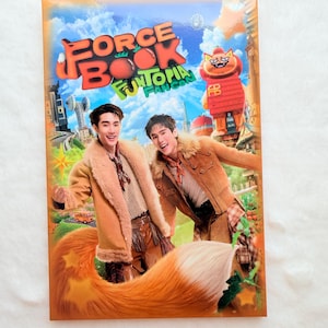May include: A book cover with the title "FORCE BOOK FUNTOPIA FANCON" in red and green lettering. The cover features two men in brown jackets with fur trim, and a large orange and white fox tail. A cartoon character is also visible.