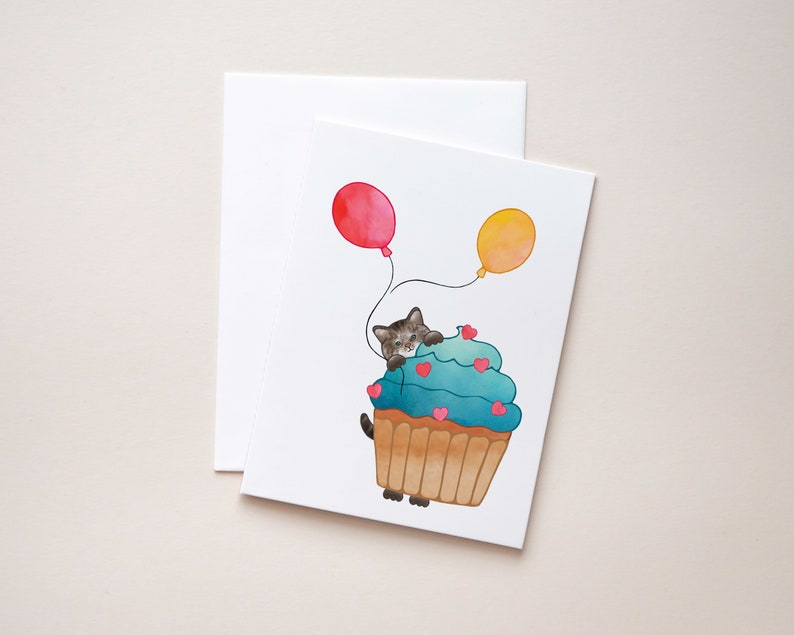 Brown Tabby Cat, Birthday Card Show some love with a sweet Tabby Cat peeking out from behind a cupcake holding balloons. image 1