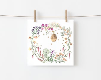May include: Watercolor print of a bee-themed design. A brown beehive is surrounded by bees and a floral wreath of purple, pink, yellow, and orange flowers. The print is square and hangs from a clothesline with wooden clips.