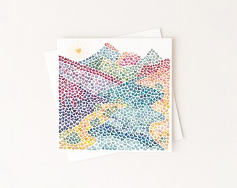 May include: A square greeting card featuring a watercolor illustration of a mountain landscape composed entirely of tiny, multicolored hearts. The scene includes a golden sun with rays in the upper left corner, with blue, purple, pink, and yellow hearts.