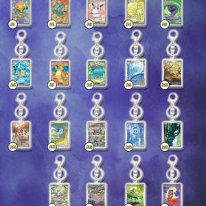 Op de afbeelding: Collectie rechthoekige sleutelhangers met verschillende Pokémon-kaartontwerpen. Elke sleutelhanger heeft een zilveren sluiting. De kaarten tonen kleurrijke illustraties van verschillende Pokémon-personages. De achtergrond is een blauwe gradiënt.