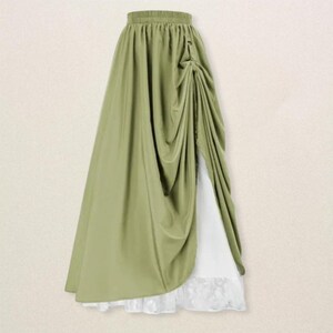 May include: A flowing, olive green skirt with a draped design. The skirt features a high waist and a side slit, revealing a white underskirt with a lace hem. The fabric has a soft, elegant drape, suitable for formal or special occasions.