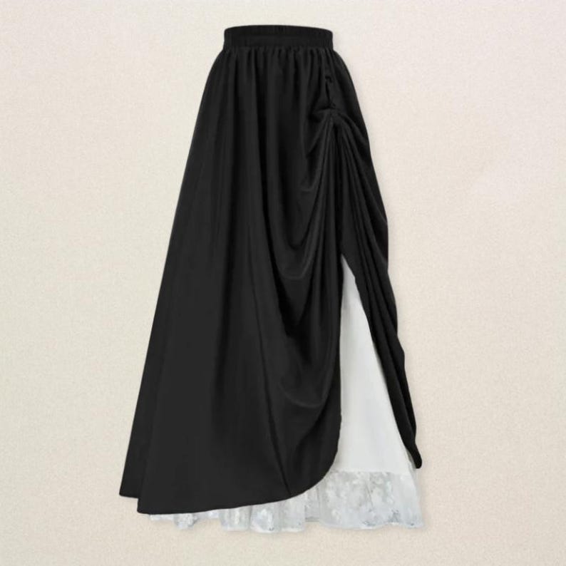 May include: A long, black skirt with a draped design and a high slit, revealing a white underskirt with a lace hem. The skirt has an elastic waistband and a flowing silhouette, suitable for various occasions.