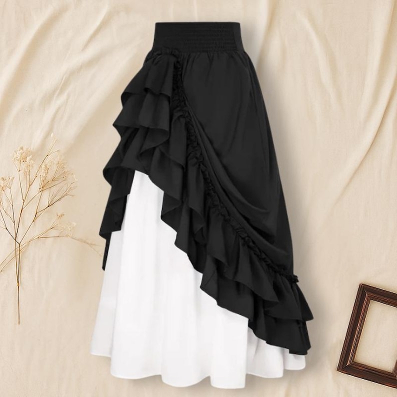 May include: A two-toned skirt featuring a black ruffled overlay over a white underskirt. The skirt has a high, elasticized waistband and a layered, asymmetrical design. The fabric appears to be lightweight and flowing.