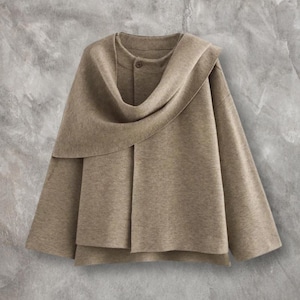 May include: A beige cape-style jacket featuring a draped cowl neckline and a single button fastening. The jacket has a layered design and a relaxed fit. The fabric appears to be a soft, woven material, suitable for layering.