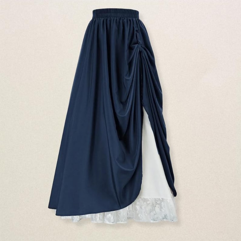 May include: A navy blue skirt with a draped design and a high waist. The skirt features a slit that reveals a white underskirt with a lace hem. The fabric has a slight sheen, and the skirt appears to be made of a flowing material.