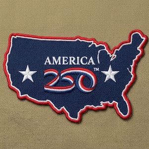 May include: A navy blue patch in the shape of the United States, outlined in red and white. The patch features the word "AMERICA" above the number "250" in red, white, and blue, with two white stars.