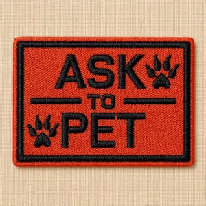 May include: A rectangular, embroidered patch with the words "ASK TO PET" in black, with paw prints. The patch has a red background and a black border. The patch is on a beige background.