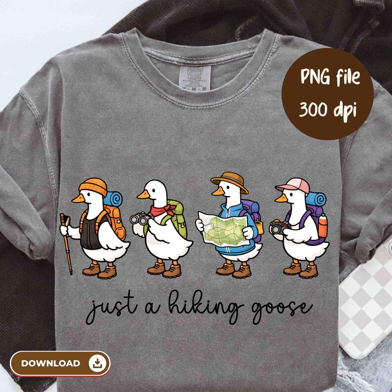 K&ouml;nnte beinhalten: Graues Langarmshirt mit vier Cartoon-G&auml;nsen, die zum Wandern gekleidet sind. Jede Gans hat einen Rucksack und Zubeh&ouml;r wie eine Karte, ein Fernglas und eine Kamera. Der Text "just a hiking goose" steht darunter.