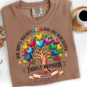 May include: A brown t-shirt with a colorful tree design featuring heart-shaped leaves. The text reads "OUR ROOTS RUN DEEP 2026 OUR LOVE RUNS DEEPER" and "FAMILY REUNION ANDERSON". The shirt has a Comfort Colors tag.