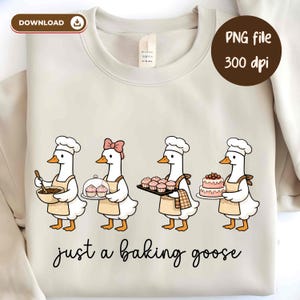 May include: Cream-colored sweatshirt featuring a whimsical illustration of four cartoon geese dressed as bakers. Each goose is holding baked goods, with the text "just a baking goose" in a script font below the illustration.