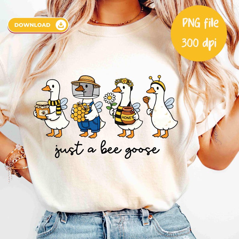 May include: Cream-colored t-shirt featuring a whimsical illustration of four geese dressed as bees and beekeepers. Each goose holds honey-related items. The text "just a bee goose" is printed below the geese. A yellow circle indicates a PNG file.