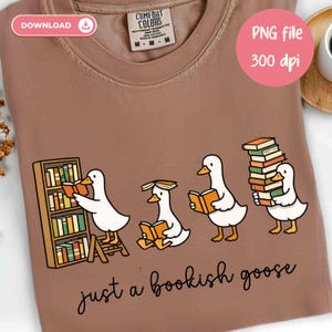 May include: A brown Comfort Colors t-shirt featuring a whimsical design of four cartoon geese reading books. One goose is on a ladder, another has a book on its head, and the last is carrying a stack of books. The text "just a bookish goose" is below the geese.