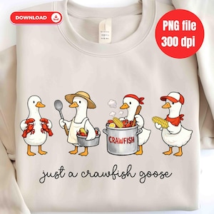 Może przedstawiać: Kremowa bluza z ilustracją czterech gęsi z kreskówek. Gęsi przedstawione są z rakami, przyborami kuchennymi i kukurydzą. Tekst "just a crawfish goose" jest napisany kursywą na dole.