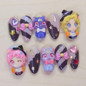 May include: A set of ten custom-designed, long, oval-shaped press-on nails. The nails feature various designs, including cartoon characters, bows, glitter, and star and moon accents. Colors include pink, purple, black, and gold.