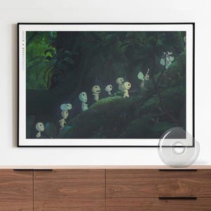May include: A framed art print depicting a forest scene with several small, white, humanoid figures with large heads. The artwork is set against a dark green background. The print is displayed above a wooden cabinet, adding a touch of nature.