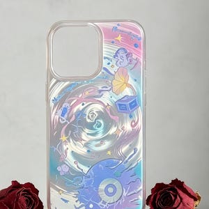 Puede incluir: Funda transparente para teléfono con un diseño iridiscente y arremolinado con elementos celestiales. La funda se exhibe sobre un pedestal blanco adornado, rodeada de rosas rojas secas y una vela negra encendida.