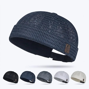 May include: A dark navy blue mesh beanie hat with a small brown rectangular tag. The hat is shown in a studio setting with four additional hats in black, navy, gray, white, and cream. The hats are a lightweight, breathable design.