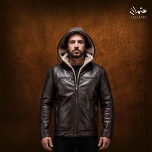 May include: A brown leather jacket with a hood lined with a light-colored fur-like material. The jacket has a zipper closure and two chest pockets. The brand name "USMAN" is visible in the upper right corner.
