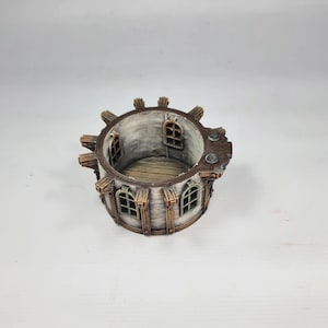 以下が含まれることがあります： 風化した外観のミニチュア円形建造物。アーチ型の窓、木製の装飾、詳細な内装が特徴で、ファンタジーや歴史をテーマにしているようです。カラーパレットは、茶色、グレー、白の色合いで構成されています。