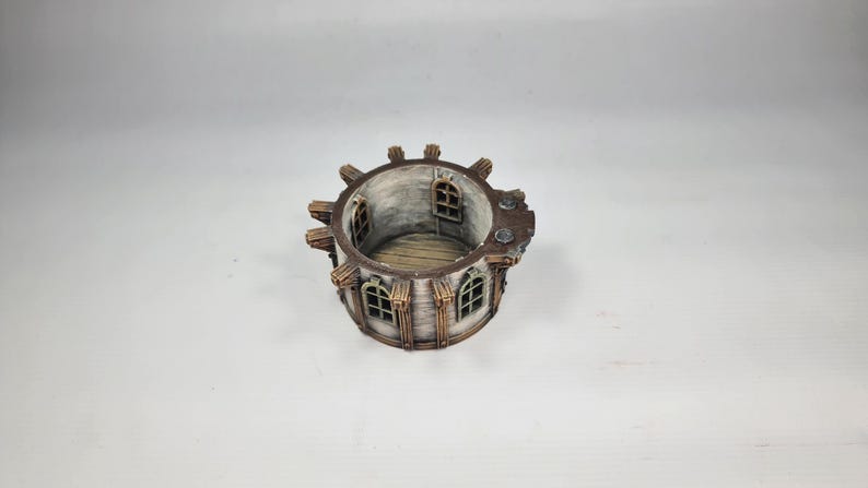 以下が含まれることがあります： 風化した外観のミニチュア円形建造物。アーチ型の窓、木製の装飾、詳細な内装が特徴で、ファンタジーや歴史をテーマにしているようです。カラーパレットは、茶色、グレー、白の色合いで構成されています。