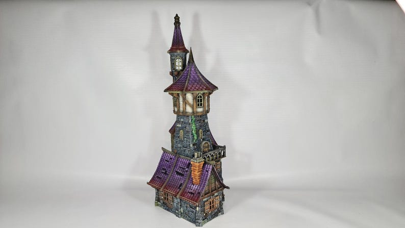 以下が含まれることがあります： 高い塔と複数の小塔を備えた、詳細なミニチュアファンタジー城。 城は紫色の屋根、石壁、小さな窓が特徴です。 全体的なデザインは気まぐれで詳細であり、建築要素に焦点を当てています。